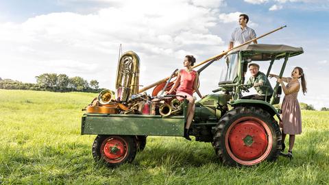 Die Wellbappn: Eine Musikkapelle auf einem Traktor, auf der Ladefläche liegen Instrumente