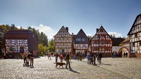 Menschen auf einem gepflasterten Marktplatz, im Hintergrund Fachwerkhäuser